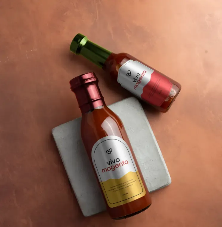 Sauce bottles with metallic red and gold labels on a stone coaster